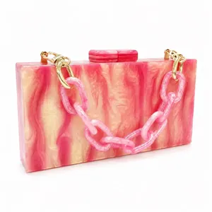 Detail of pink marble acrylic evening clutch with thick chain strap and gold hardware
