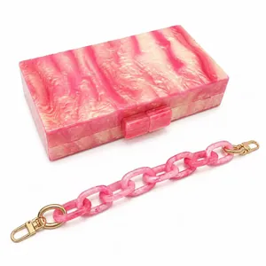 Detail of pink marble acrylic clutch bag with matching thick chain and gold hardware