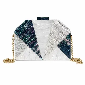 Detail of hexagonal acrylic clutch with marble textures and gold chain strap