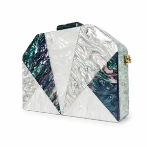 Detail of geometric acrylic evening clutch with marble texture and gold hardware