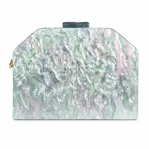 Detail of acrylic clutch with marble texture and gold hardware on white background