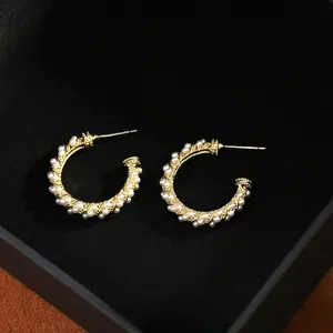 Close-up of S925 sterling silver stamp on C-shaped gold hoop earrings with white pearls