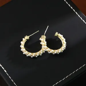 Elegant gold-tone C-shaped hoop earrings with twisted metal design and white pearls