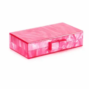 Detail of pink marble acrylic clutch bag with modern square clasp and smooth finish