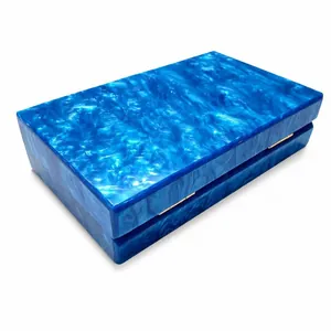 Macro detail of dark blue marble texture and golden hinge on rectangular acrylic clutch bag
