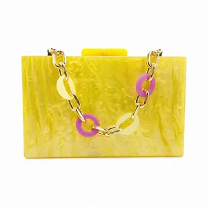 Détail de pochette en acrylique jaune marbré avec chaîne dorée et anneaux mauves