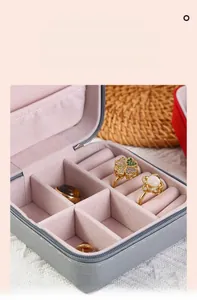 Detailed interior of a grey leather jewelry box with velvet ring slots and storage sections