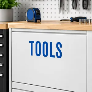 Close-up of bold blue TOOLS letter sticker on a white metal storage cabinet drawer