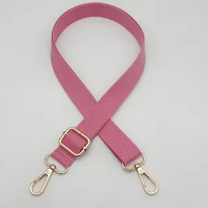 Détail d'une bandoulière rose en nylon tissé avec boucle réglable en métal doré brillant
