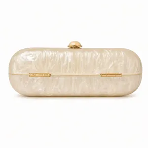 Macro shot of oval acrylic evening bag featuring pearlescent texture and gold metal clasp