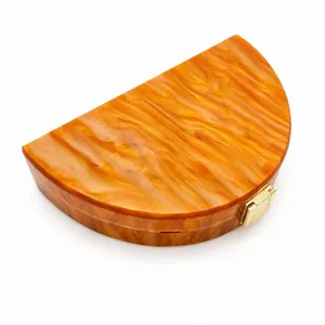 Detail view of amber marble acrylic clutch with elegant golden clasp for evening