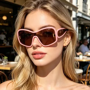 Close-up of pink oversized sunglasses with brown lenses worn in a stylish city setting