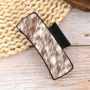 Western style cow print faux fur hair claw clip in matte black finish on a natural mat