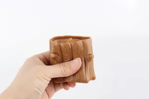 Detail showing a hand squeezing the brown tree stump to pop out the squirrel toy