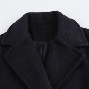 Detail of notch lapel on black wool coat featuring thick textured fabric and neat stitching