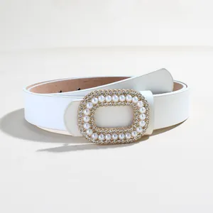 Dettaglio cintura in pelle bianca con fibbia dorata decorata con perle e strass