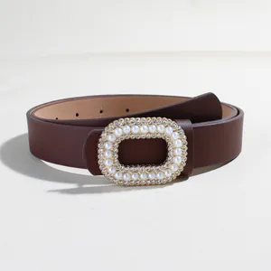 Dettaglio cintura in pelle marrone con fibbia decorata con perle e strass