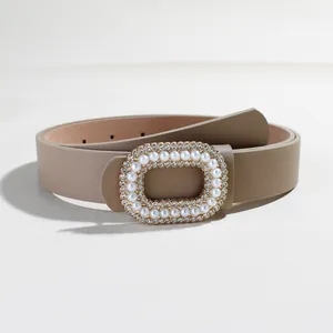 Dettaglio della fibbia rettangolare con perle e strass su cintura in pelle color kaki