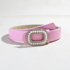 Dettaglio cintura in pelle rosa con fibbia ovale decorata con perle e strass luccicanti