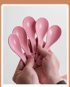 Set of five matte pink ceramic spoons held by hand to show sleek texture and round hole