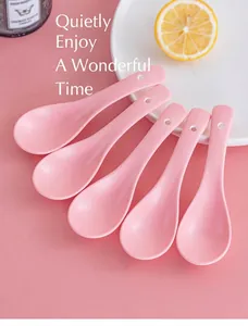 Close-up of pink ceramic spoons set on a white plate with a lemon slice and candle