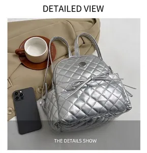 Detail of silver quilted backpack showing metallic PU leather and bow with magnetic closure