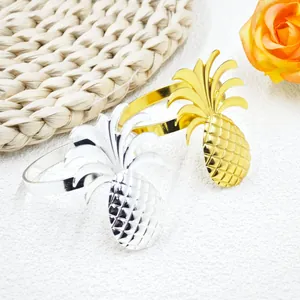 Elegant gold and silver pineapple napkin rings displayed with floral decor on white background