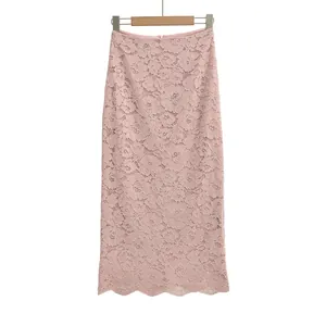 Close-up of elegant floral lace texture and scalloped hem on a light pink midi skirt