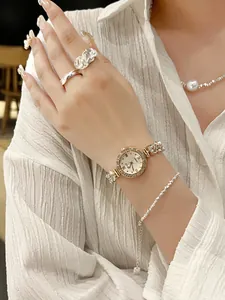 Details einer luxuriösen roségoldenen Uhr mit Kristalllünette und feiner Metallkette
