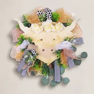 Highland cow floral wreath with eucalyptus leaves and multi-colored ribbons on white door