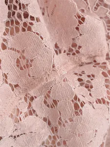 Close-up of pink floral embroidery lace fabric with intricate mesh and fine stitching