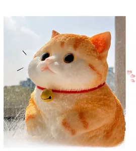 Close-up of orange and white flocked cat figurine with red collar and golden bell detail