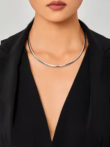 Gros plan détaillé d'un collier chaîne oméga argenté flexible porté avec un costume noir
