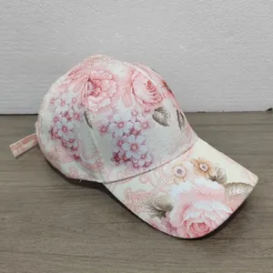 Macro detail of the floral cotton baseball cap with pink rose patterns on a wooden surface