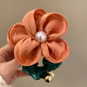 Floral scrunchie in orange-pink satin with large pearl center and green elastic band