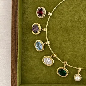 Macro detail of oval multi-color birthstone pendants and a pearl on a gold chain