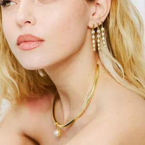Detail shot of a gold choker with pearl drop and cascading crystal earrings on a model
