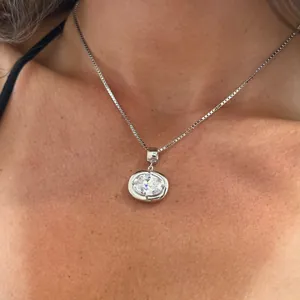Close-up of a silver box chain necklace with an oval cut clear zircon pendant for women