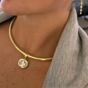 Close-up of golden choker with round crystal pendant and matching long chain zircon earrings
