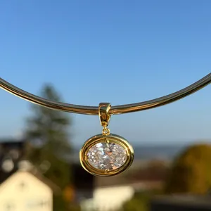 Macro shot of an oval clear gemstone pendant on a gold choker against a blue sky