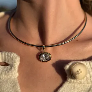 Close-up of golden choker with a large oval clear gemstone on a model in a knit cardigan