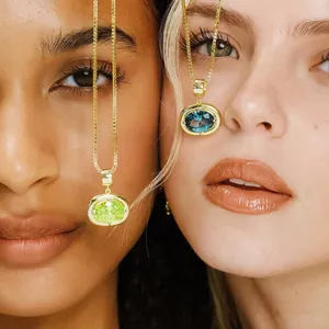 Close-up of gold necklaces featuring oval peridot green and topaz blue zircon pendants