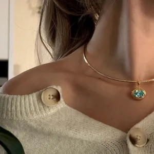Detail of elegant gold choker with an oval light blue gemstone pendant on a model