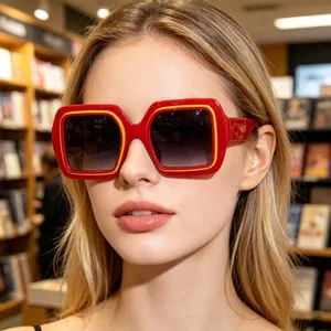 Gros plan de lunettes de soleil carrées avec monture rouge et liseré jaune sur modèle