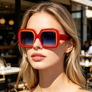 Détail de lunettes de soleil carrées rouges avec des accents jaunes portées par le mannequin
