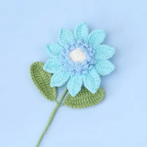 Handgehäkelte hellblaue Sonnenblume mit grünen Blättern auf hellblauem Hintergrund