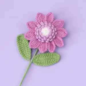 Handgefertigte lila Häkelblume mit gestuften Blütenblättern und grünen Blättern am Stiel