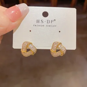 Macro shot of gold-plated knot earrings encrusted with micro-pave cubic zirconia crystals