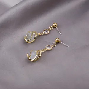 Detail of long tassel earrings with cat-eye stone wrapped in gold cage on silk