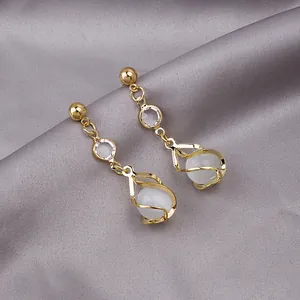 Detail of elegant gold tassel earrings with pearls and crystals on silk background